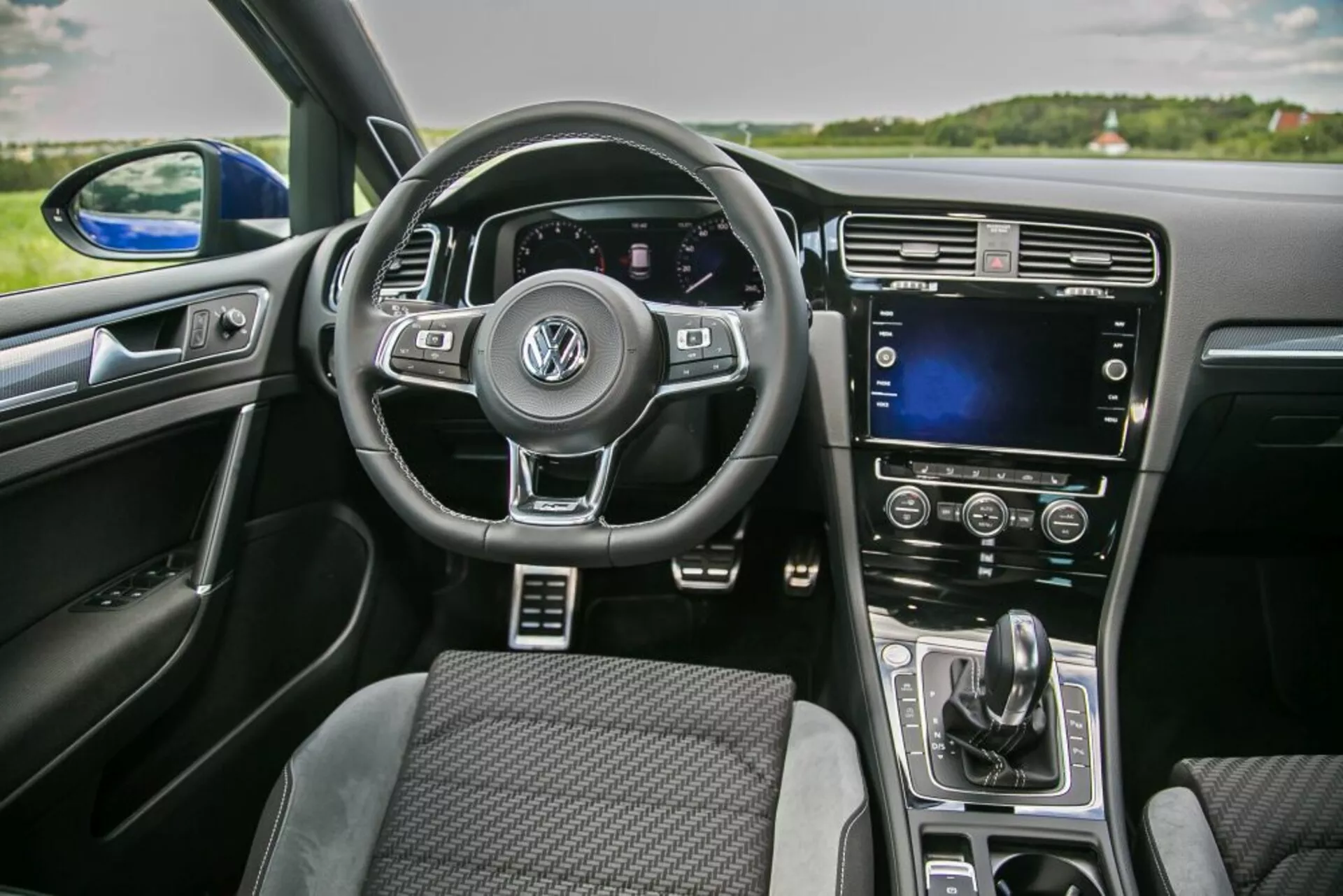Interior view of a 2019 Skoda Scala from the front passenger perspective featuring a multi-function steering wheel with Volkswagen logo, digital instrument cluster, center console touchscreen, and automatic climate control