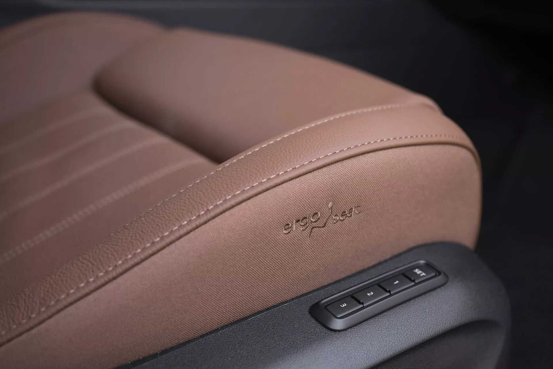 Close-up of a Skoda Superb 2024 Combi seat showing detailed stitching, 'ergo-jets' embossed upholstery, and electronic adjustment controls in high-quality brown leather