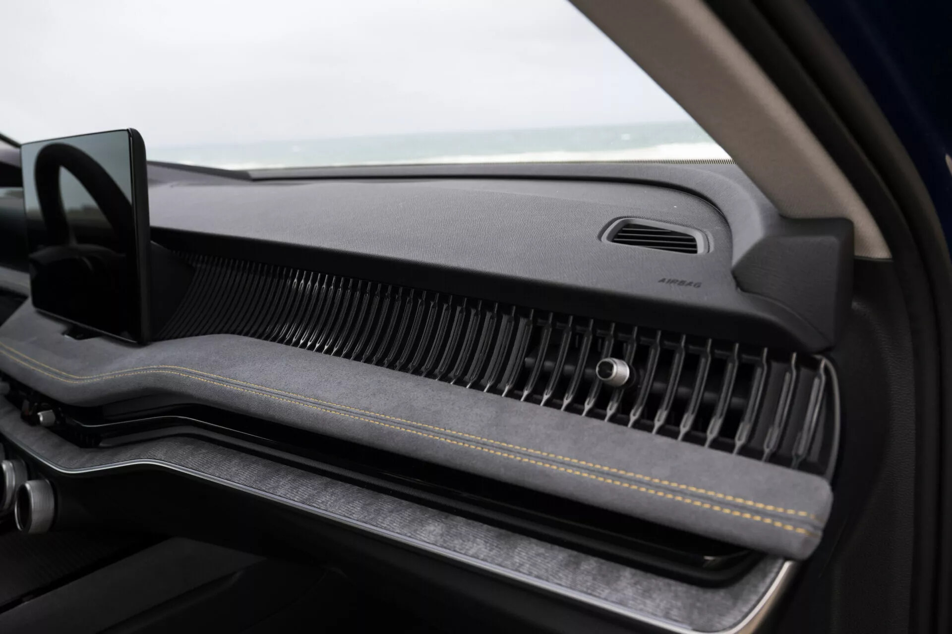 Close-up view inside Skoda Superb Combi 2024, focusing on the passenger's dashboard with minimalist design, premium air vent, and glove compartment
