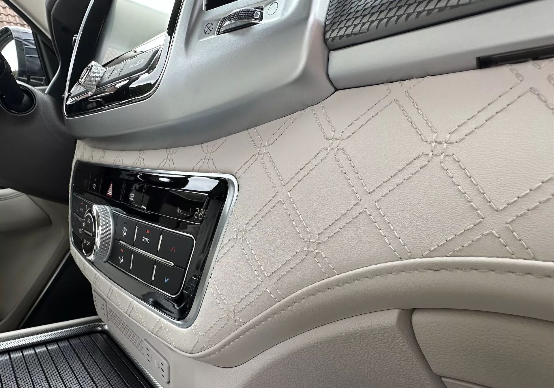 2021 SsangYong Rexton interior focusing on passenger side dashboard and front door panel with diamond-stitched leather, infotainment controls, and luxury wood trim details