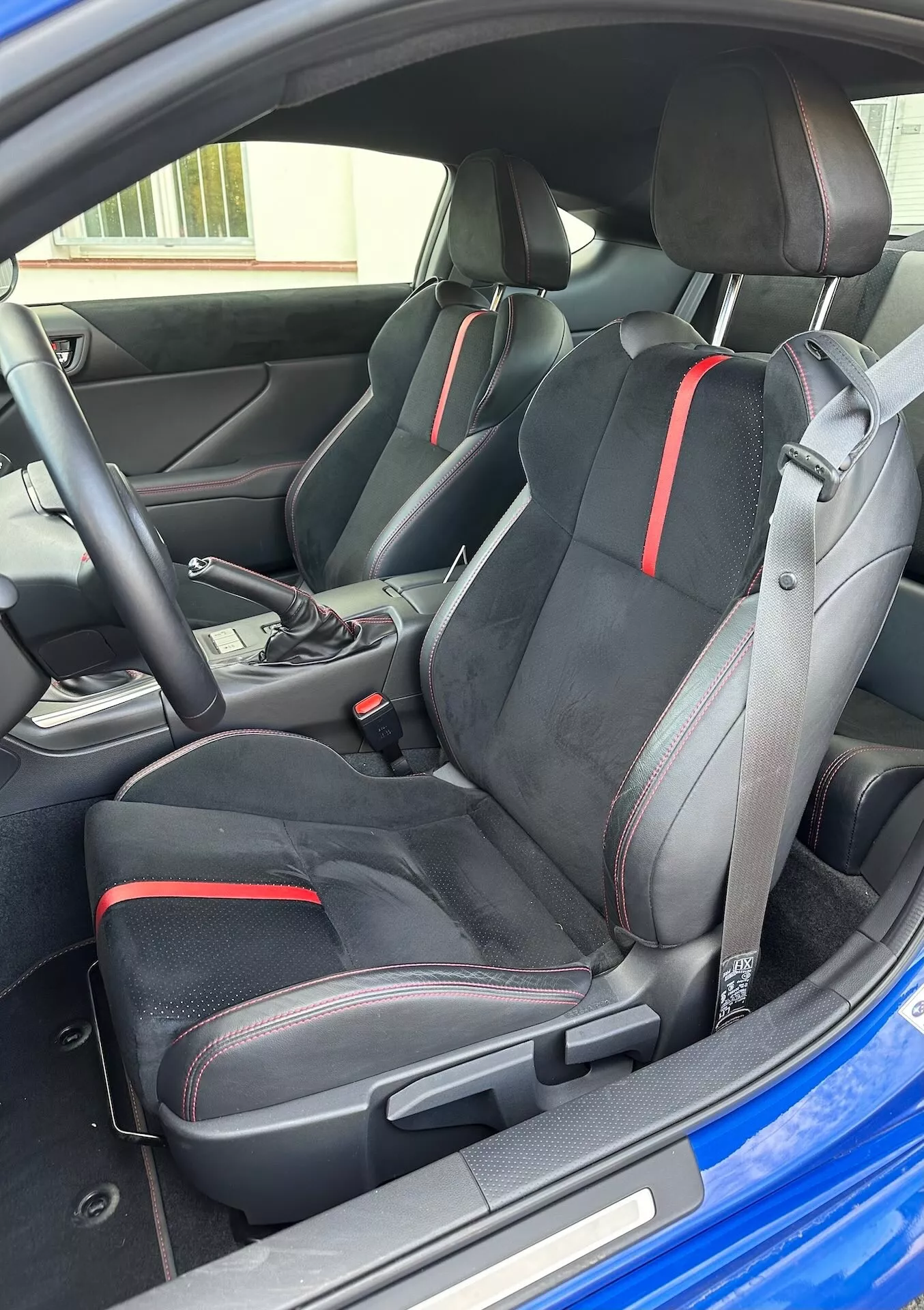 2023 Subaru BRZ interior view highlighting the sporty front seats with ergonomic design and red detailing, automatic transmission selector, and modern cockpit aesthetics from an oblique exterior perspective
