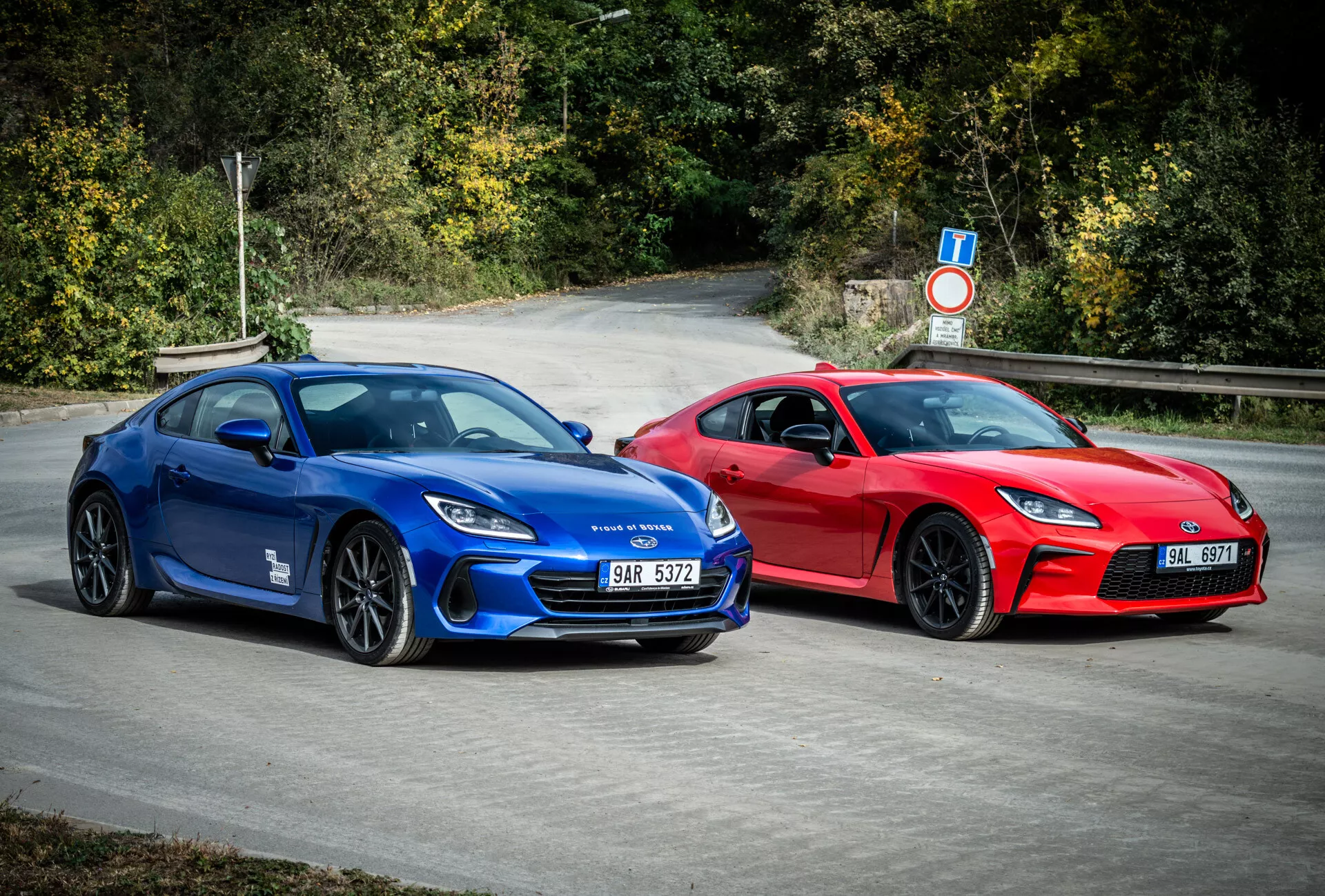 2023 Subaru BRZ sporty coupes in blue and red with aerodynamic design and performance features, parked outdoors surrounded by natural foliage