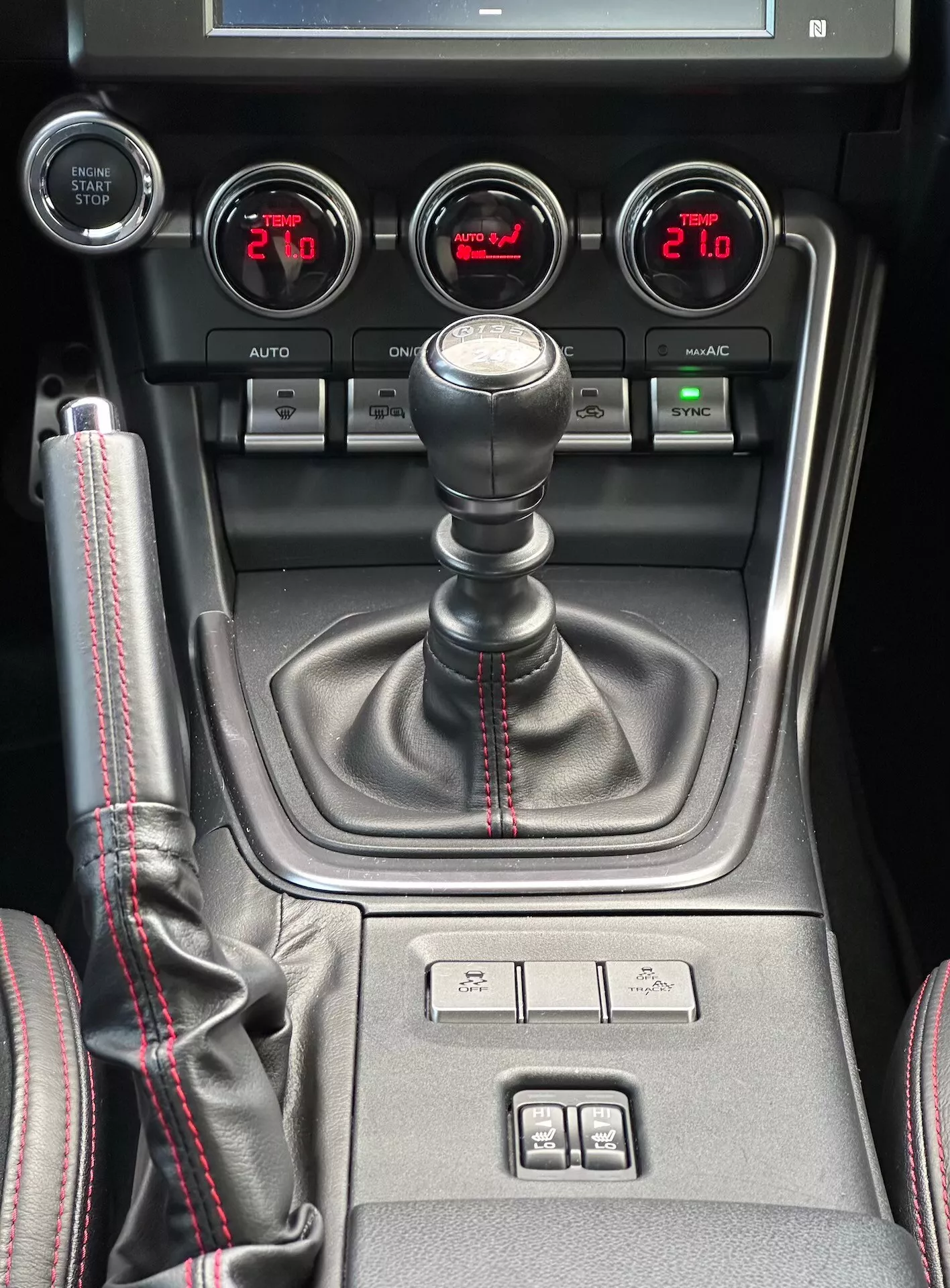 2023 Subaru BRZ central console featuring manual transmission shifter with sporty red stitching, auxiliary gauges for turbo pressure, battery voltage, oil temperature, and dual-zone climate control in detailed interior view