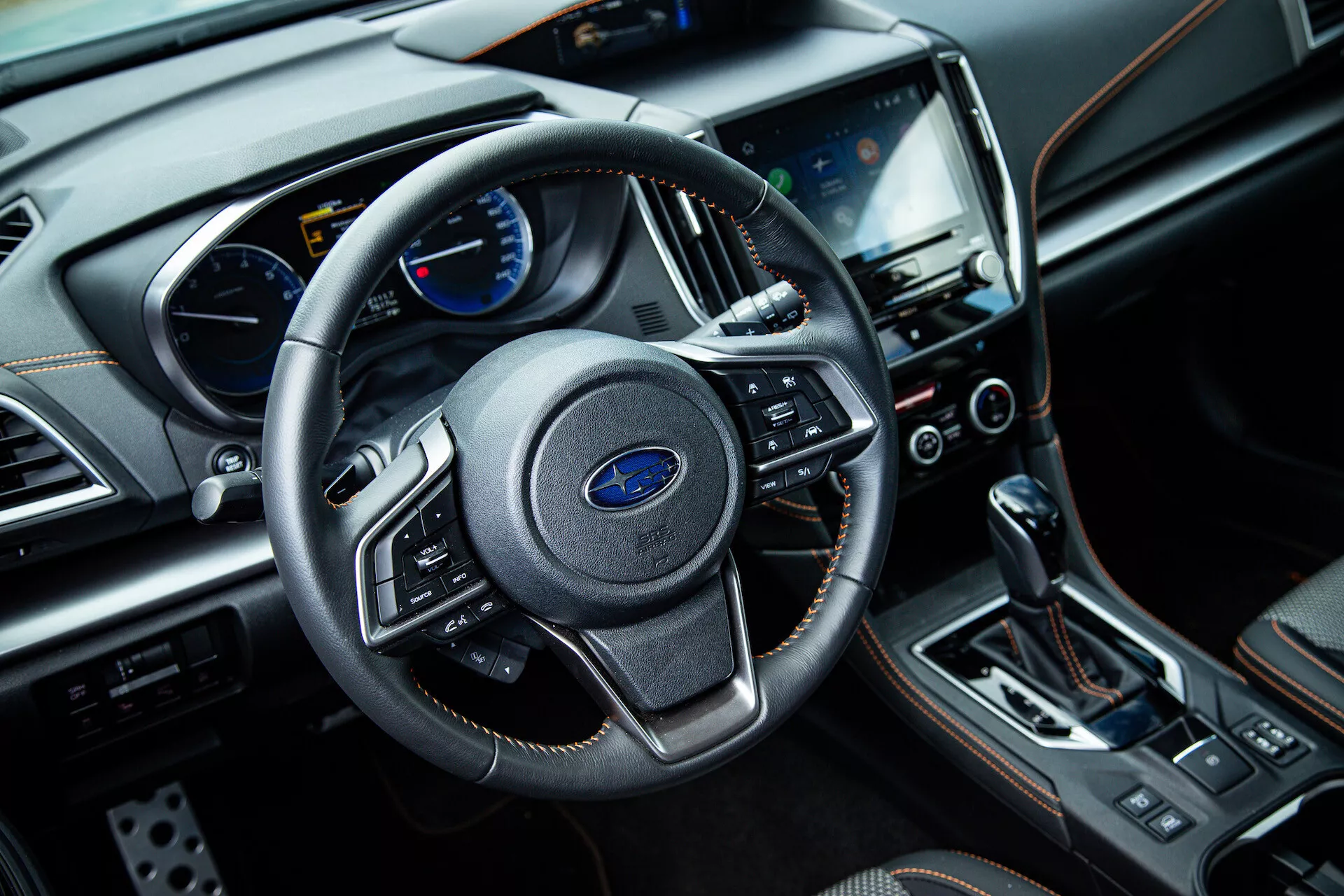 2021 Subaru XV interior view from front passenger side showing three-spoke steering wheel with multifunction controls, instrument cluster with analog and digital displays on dashboard, central touchscreen infotainment system, climate control buttons, automatic gear shift lever, and luxury finish materials, including leather and chrome accents.