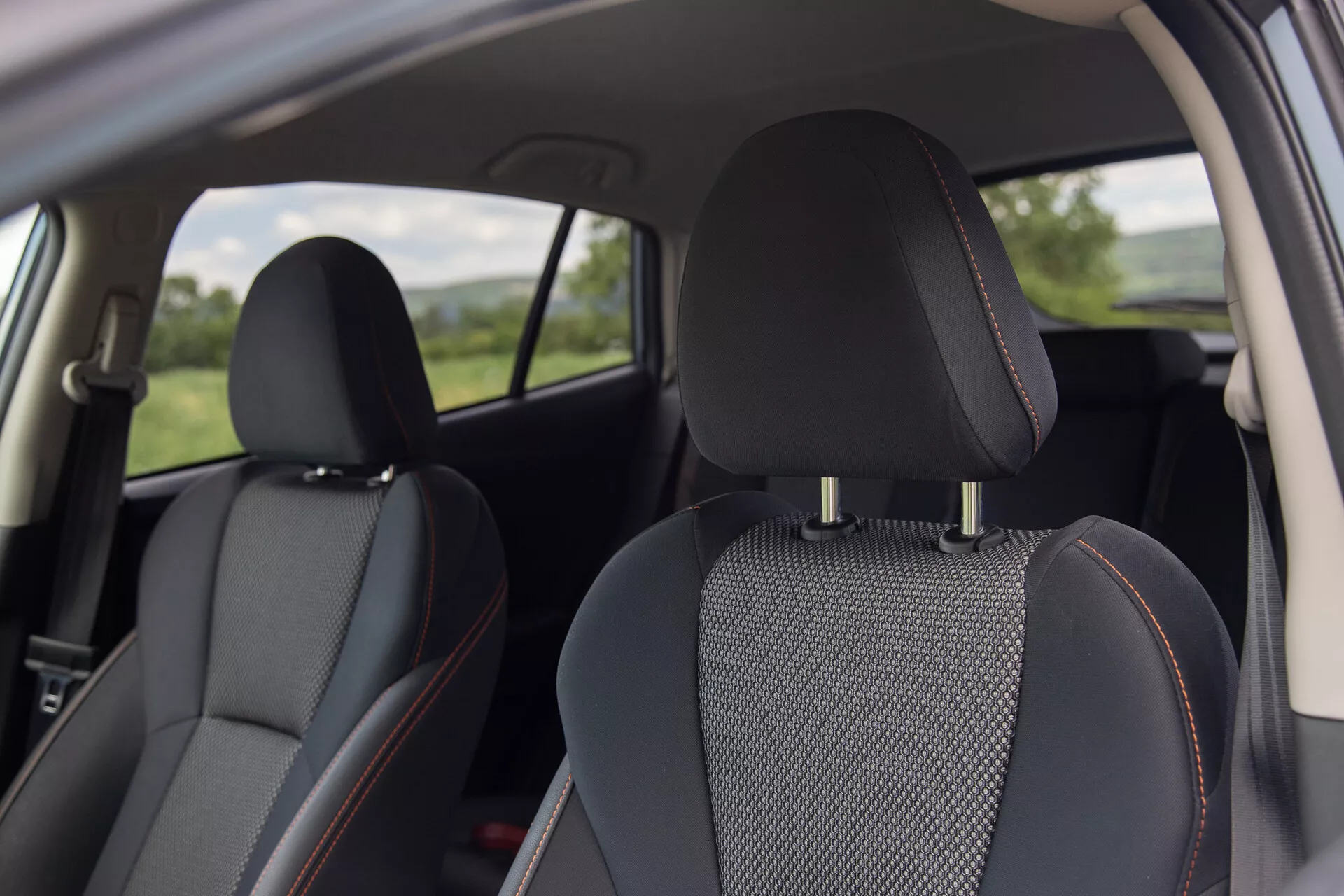 Interior view of Subaru XV 2021 featuring black leather seats with patterned fabric inserts and distinctive orange stitching, focusing on comfort and design from a rear passenger perspective