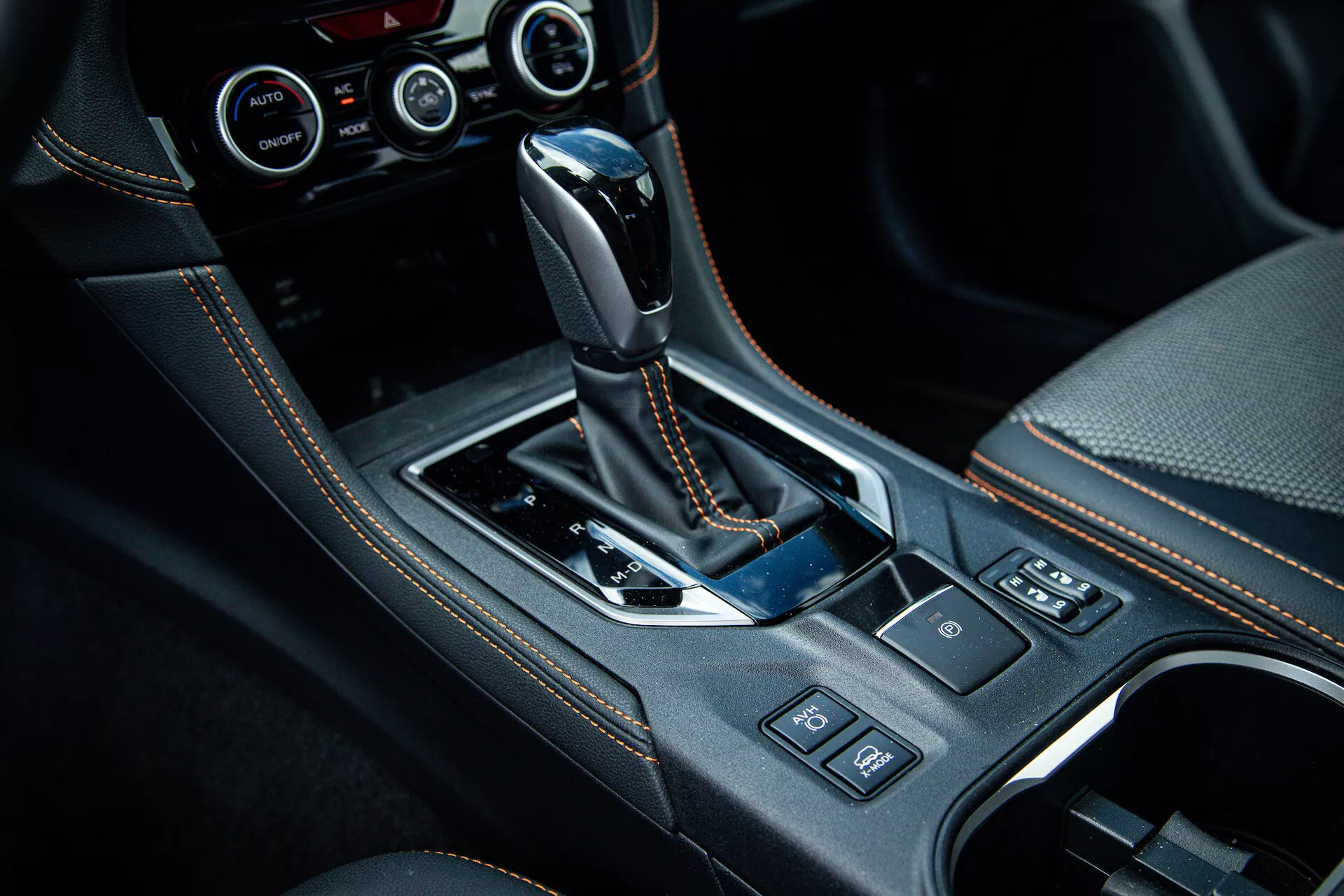 2021 Subaru XV center console with automatic gear shift lever wrapped in leather, glossy black trim, chrome details, cupholders, control buttons, and advanced climate control system visible in high-quality interior photo