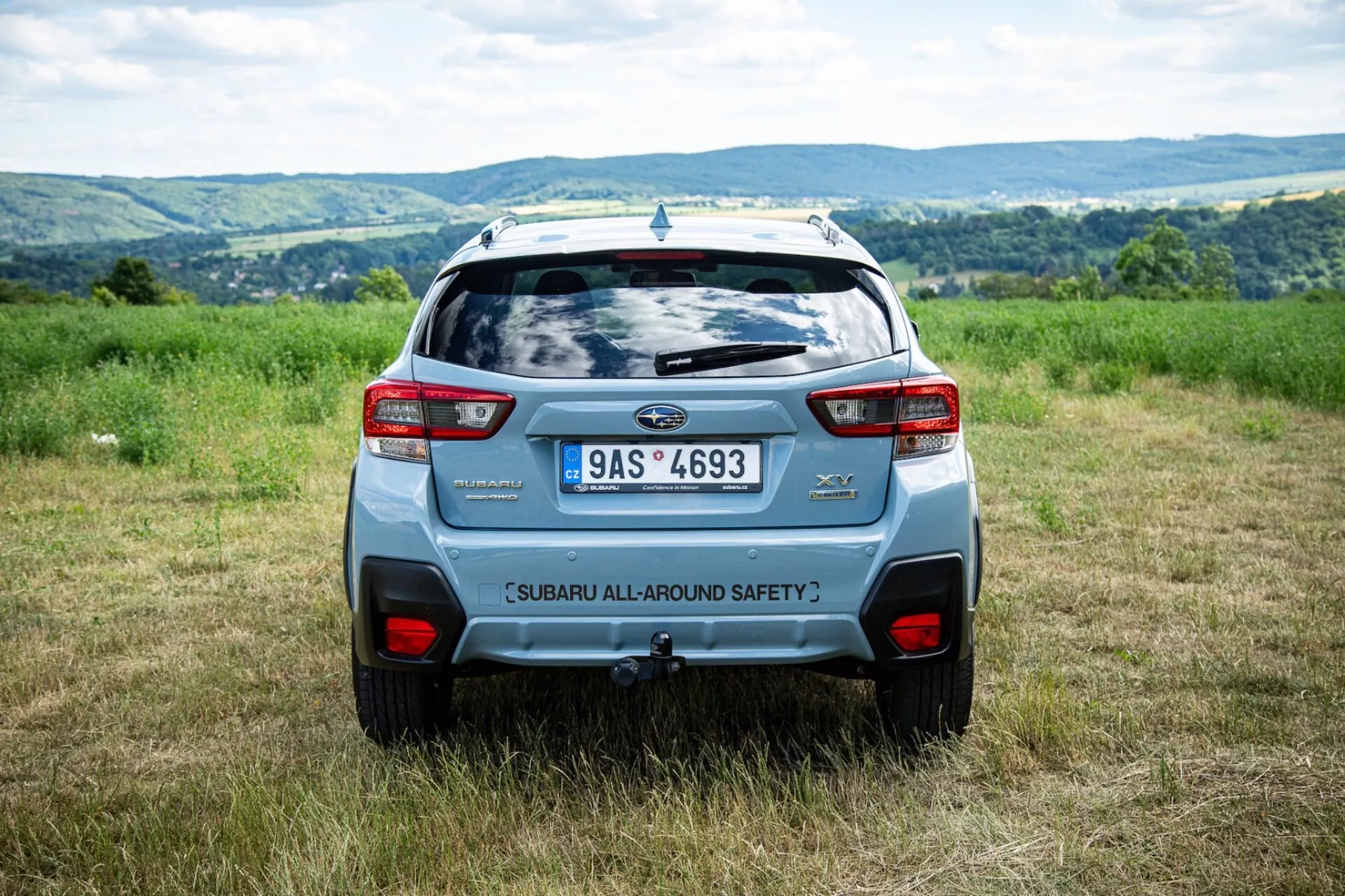2021 Subaru XV rear angle view outdoors in a field with hilly backdrop, highlighting safety features and modern SUV design elements like rear spoiler and bold taillights