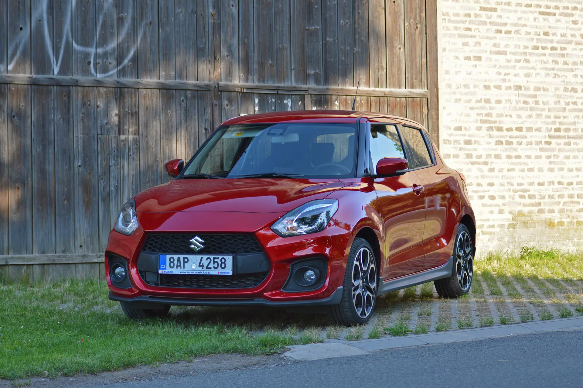 2017 Suzuki Swift Sport in vibrant red finish, front three-quarter view, showcasing sporty design, sharp headlights, aggressive front grille, alloy wheels, and aerodynamic side skirts
