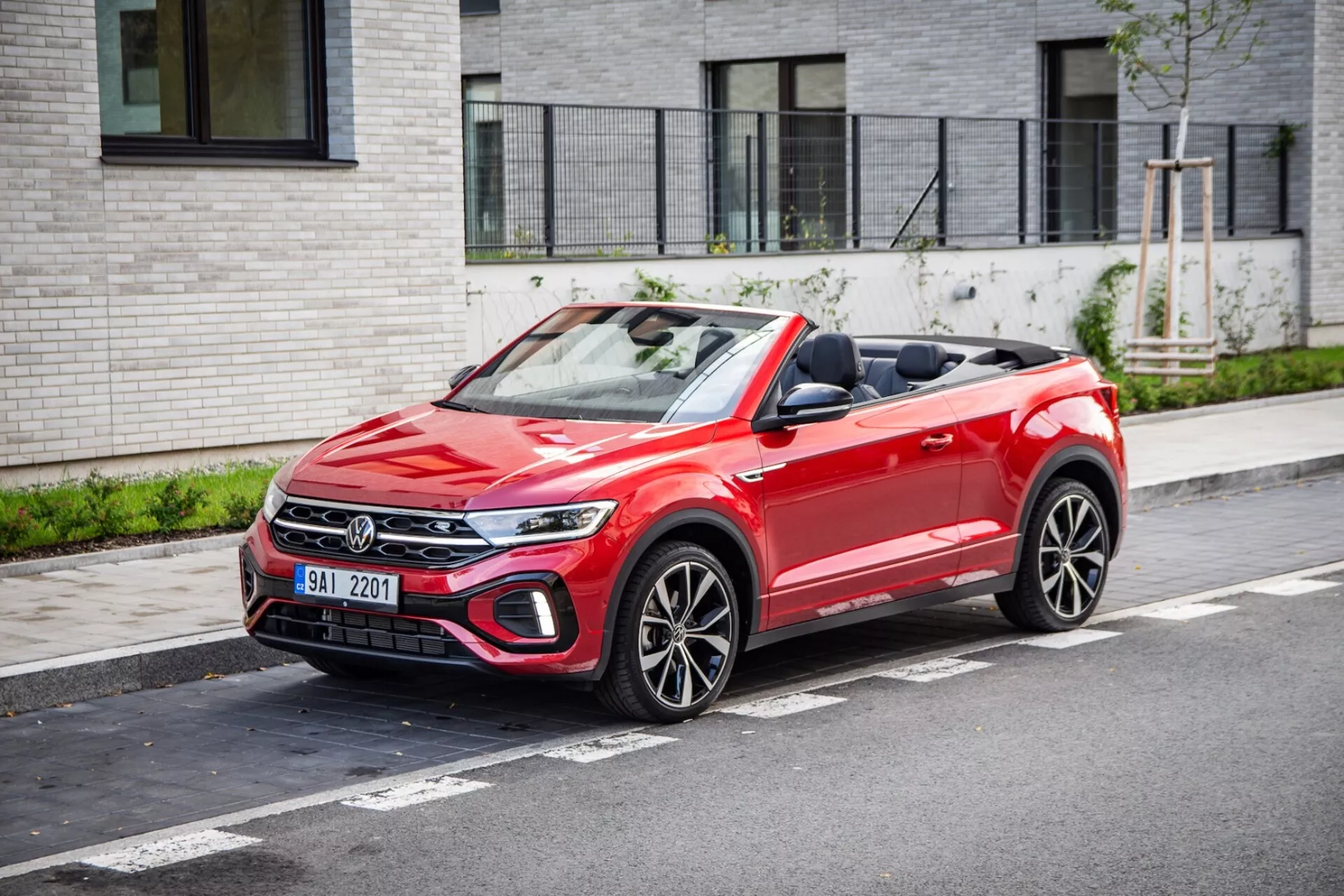 2022 VW T-Roc Cabriolet parked on urban street showing front grille, LED headlamps, fabric convertible top down, and sporty multi-spoke wheels