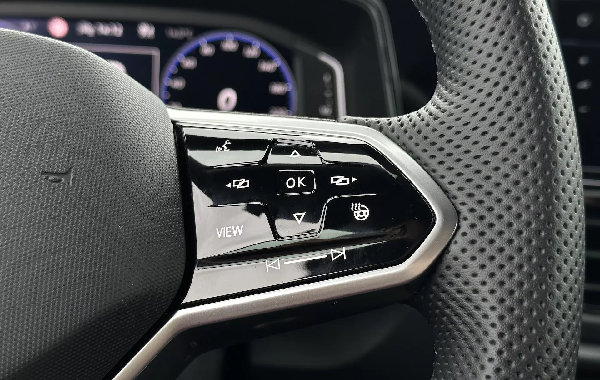 Close-up of the multifunction steering wheel controls on a 2022 VW T-Roc Cabriolet, showcasing ergonomic design and interactive buttons for infotainment and vehicle settings