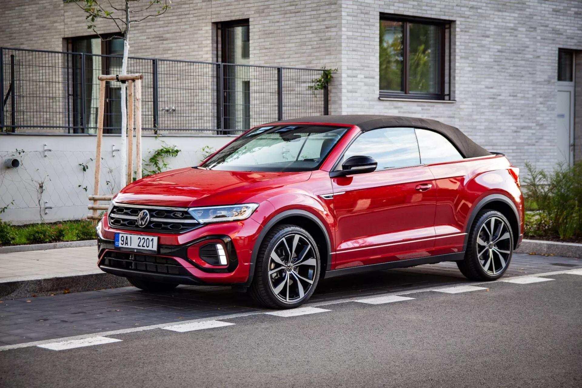2022 VW T-Roc Cabriolet bright red convertible crossover SUV parked street-side, showcasing front grille, LED headlights, alloy wheels, and soft top, in a clear weather three-quarter front view