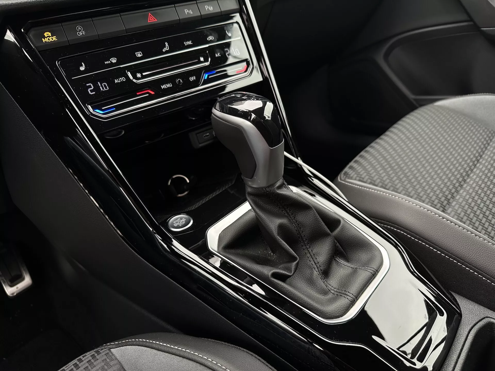 Close-up view of VW T-Roc Cabriolet 2022 center console with automatic transmission gear shift, dual-zone climate control, seat heating and ventilation buttons, and control display panel