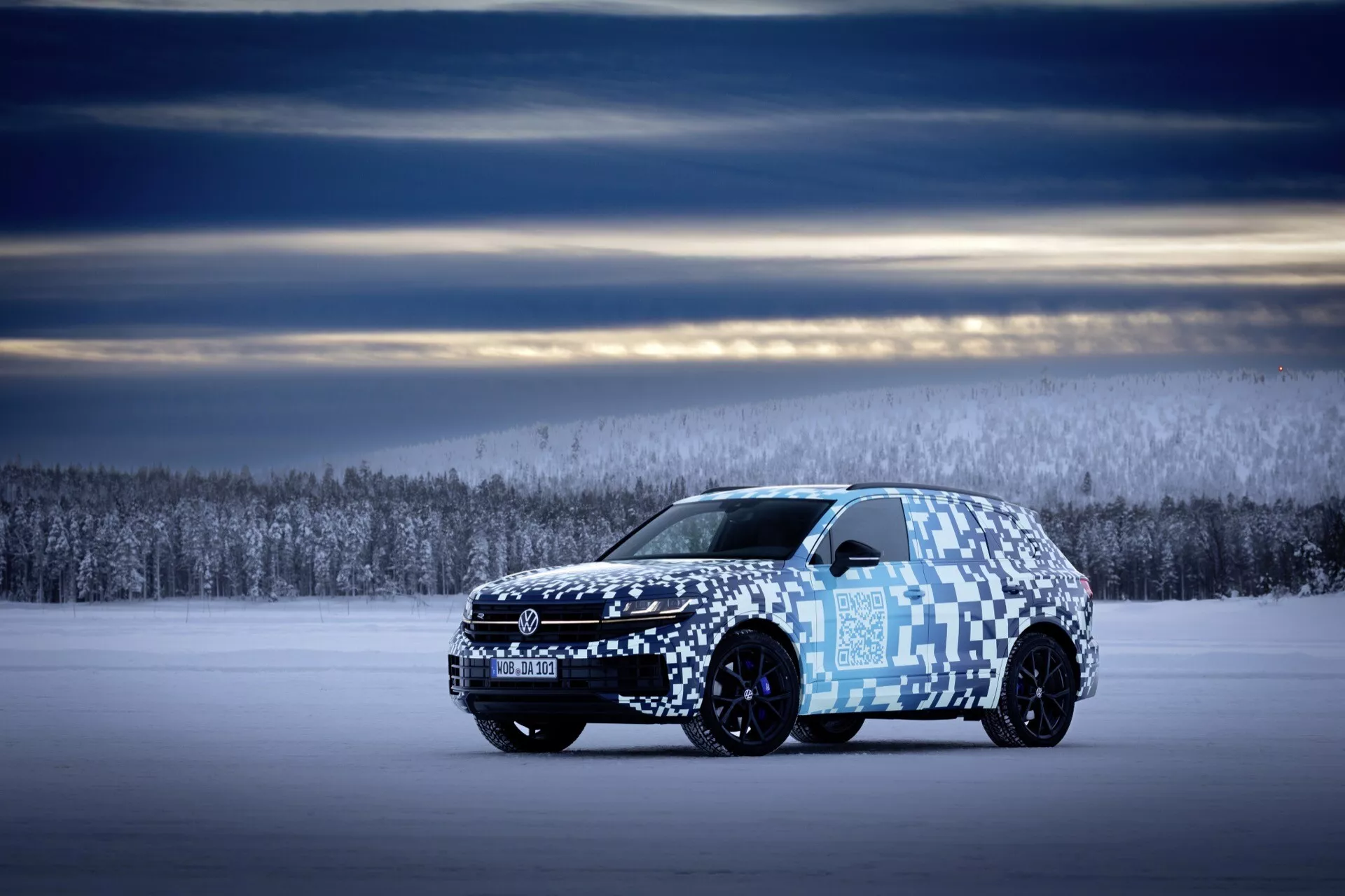 2023 Volkswagen Touareg III facelift side profile view on snowy terrain with camouflage wrap showcasing vehicle length, aerodynamic design, and advanced lighting system