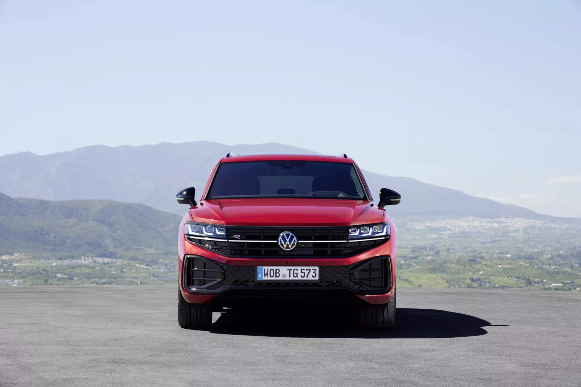 Front view of a red 2023 Volkswagen Touareg III facelift showing the integrated grille and LED headlight clusters, enhancing the vehicle's dominance and modern technology features