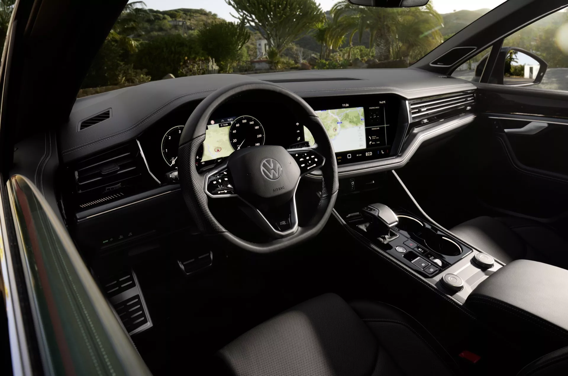 Volkswagen Touareg 2023 interior showcasing a three-spoke steering wheel with brand logo, fully digital instrument cluster, large infotainment touchscreen, and stylish gear shift lever, emphasizing modern car design and advanced technology features